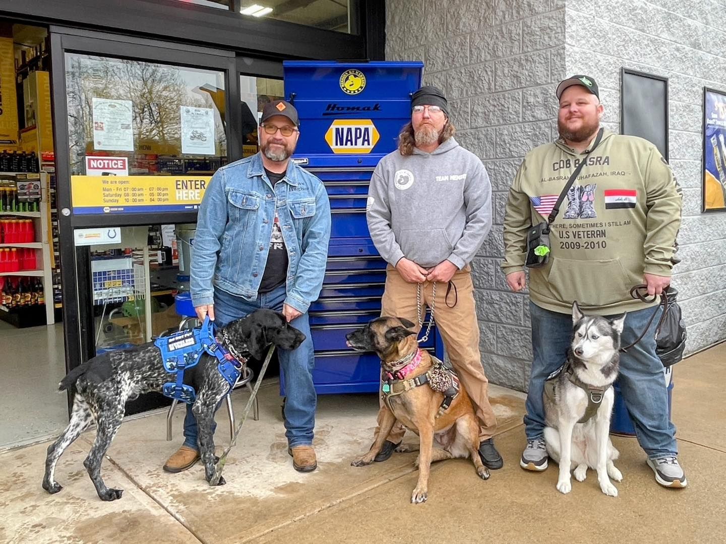 Customers and their dogs outside the Danville store by a NAPA tool box